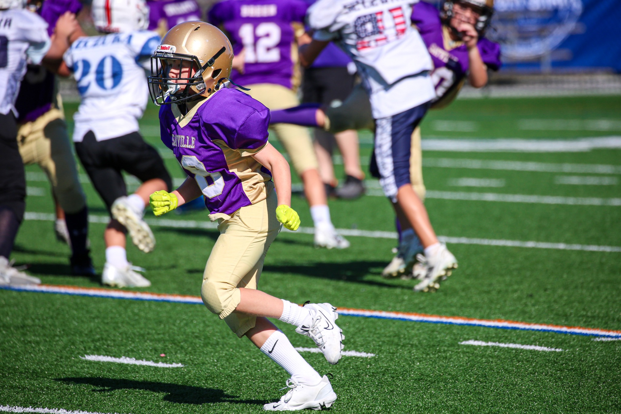 Youth football player in purple and gold running during game action